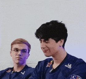 two young men are sitting next to each other and one of them is wearing a red bull shirt