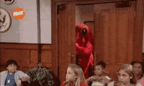 a group of children are sitting in a room with a red parrot in the background .