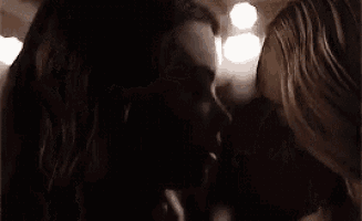 two women are looking at each other in the dark in a room .