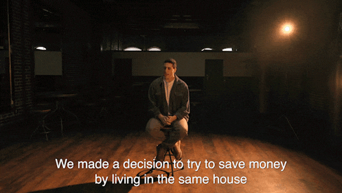 a man sitting on a stool with the words " we made a decision to try to save money by living in the same house " behind him