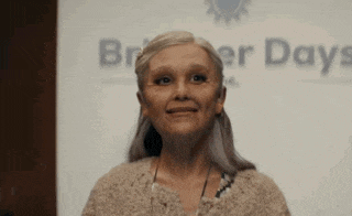 a woman with a fake face is smiling in front of a sign that says `` broken days '' .