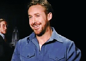 a man with a beard wearing a blue shirt is smiling in a dark room .