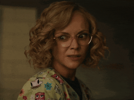 a close up of a woman wearing glasses and a green scrub top with owls on it