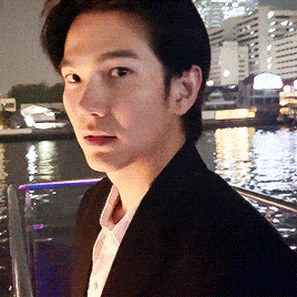 a man in a suit is standing in front of a body of water at night