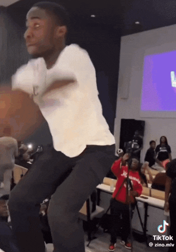 a man in a white shirt and black pants is dancing in front of a group of people .