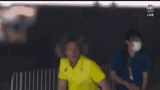 a man in a yellow shirt is standing next to a man in a blue shirt .