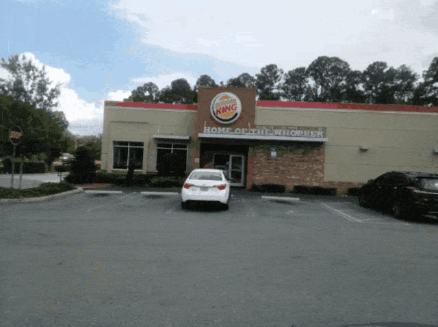 a white car is parked outside of a burger king restaurant