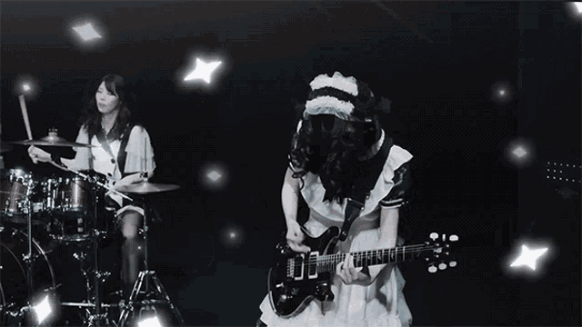 a girl in a white dress is playing a guitar in front of a drum set