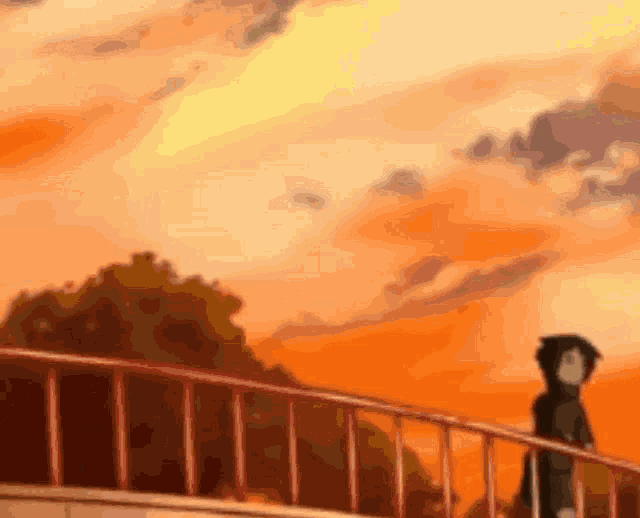 a person is standing on a bridge overlooking a sunset