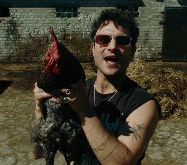 a man wearing sunglasses is holding a rooster in his hands