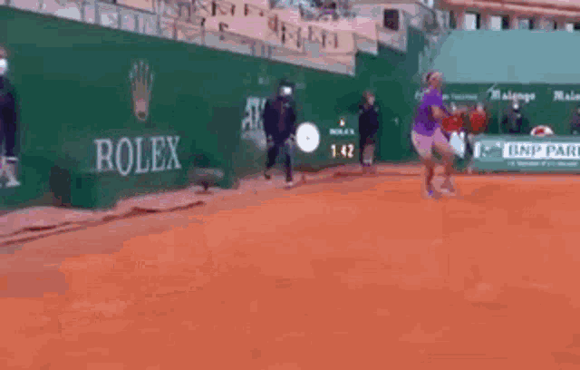 a man in a purple shirt is playing tennis on a court .