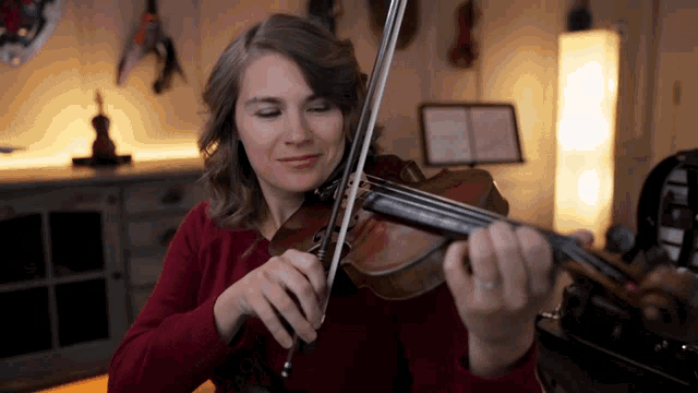 a woman is playing a violin in a room
