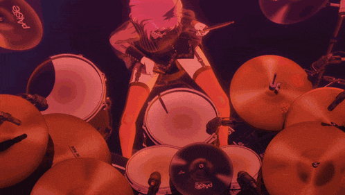 a woman is playing drums with a paiste cymbal in the foreground