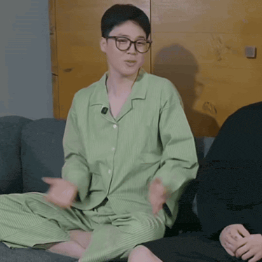 a man in a green pajama set sits on a couch