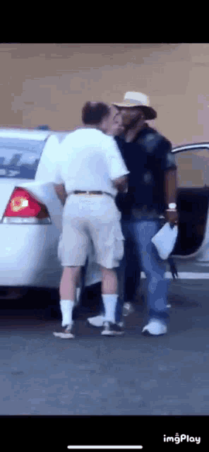 a man in a cowboy hat is standing next to a man in a white shirt and shorts .
