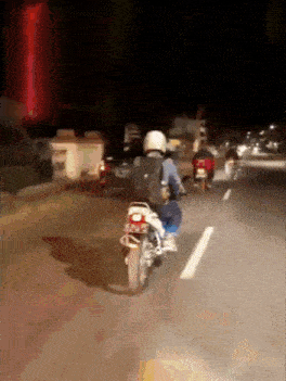 a man is riding a motorcycle down a road at night