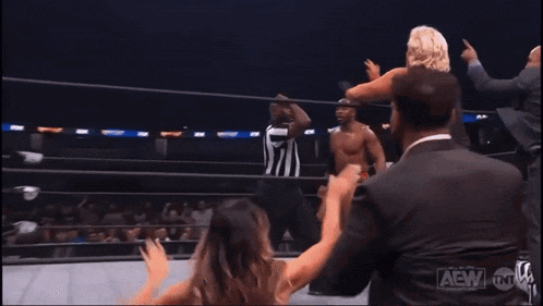 a referee is standing in the middle of a wrestling ring while two women are fighting .