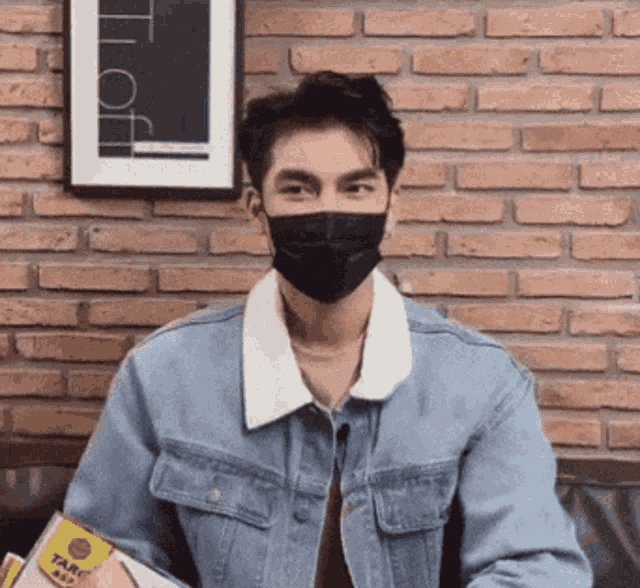 a man wearing a mask and a denim jacket is holding a box that says taro on it