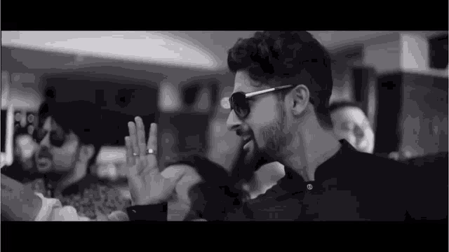 a black and white photo of a man wearing sunglasses and a wedding ring