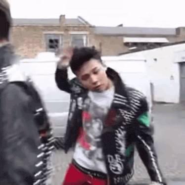 a man in a leather jacket is standing next to another man in a white shirt .