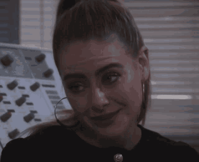 a woman with a ponytail and hoop earrings is making a face