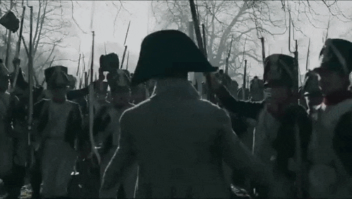 a man in a napoleon hat is standing in front of a large group of soldiers