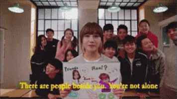 a group of people are standing around a girl holding a sign that says " there are people beside you "