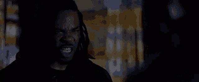 a man with dreadlocks is screaming in the dark .