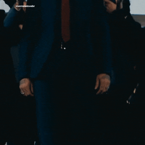a man in a suit and tie stands in front of a crowd of people