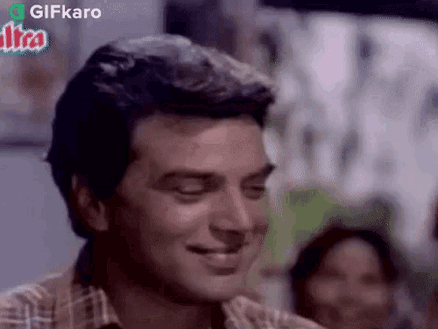 a man in a plaid shirt is smiling with his eyes closed in a movie .