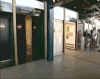 a group of people standing in front of an elevator that says anxomat arrivals