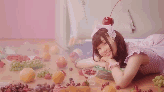 a girl with a cherry on her head is laying on the floor with fruit around her