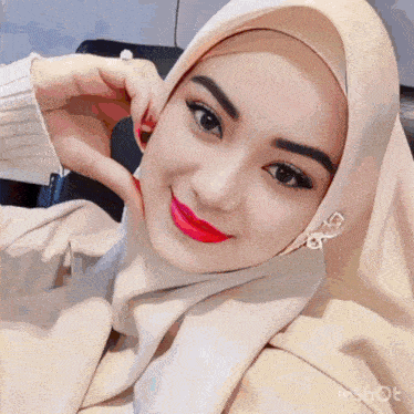 a woman wearing a hijab making a heart with her hands