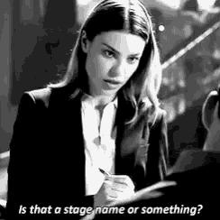 a woman in a suit is writing on a piece of paper and talking to another woman .