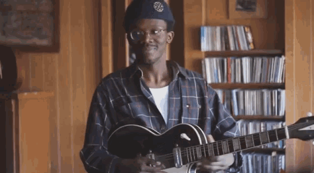 a man in a plaid shirt is holding a guitar