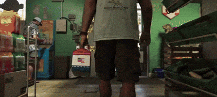 a man carrying a cooler in a store with a shirt that says ' jackson county ' on the front