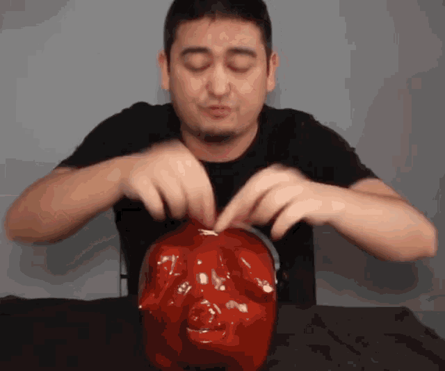a man in a black shirt is putting a coin into a red piggy bank