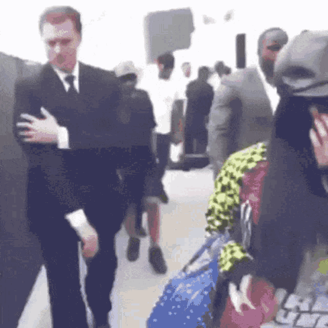 a man in a suit and tie is walking down a hallway with people .