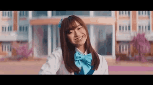 a girl in a school uniform is smiling in front of a school building .