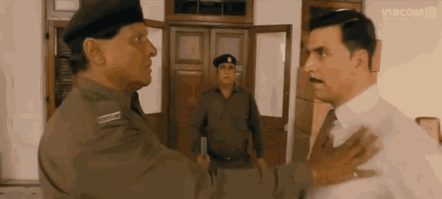 a man in a suit and tie is talking to a man in a military uniform with a badge that says " commander "