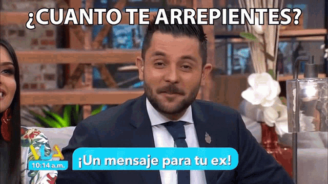 a man in a suit and tie is sitting in front of a sign that says un mensaje para tu ex