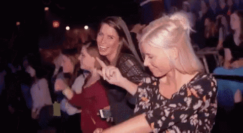 a group of women are dancing together in a dark room at a party .