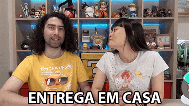 a man and a woman are sitting in front of a shelf full of toys and a sign that says entrega em casa on it