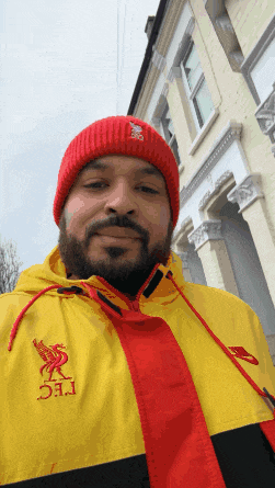 a man wearing a red beanie and a yellow jacket with the letters lfc on the front