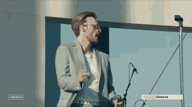 a man in a suit singing into a microphone with the word finneas on the bottom of the screen