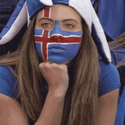 a woman with a cross painted on her face is wearing a hat