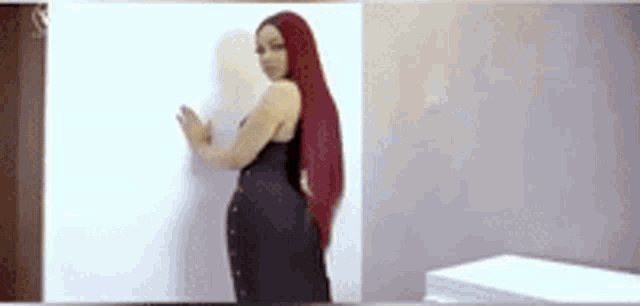 a woman with long red hair is leaning against a wall .