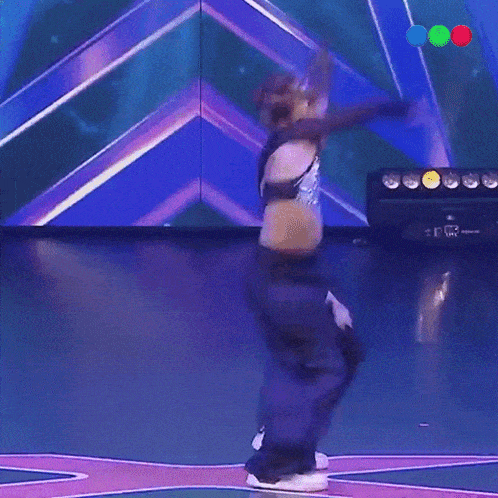 a young girl is dancing on a stage in front of a blue background