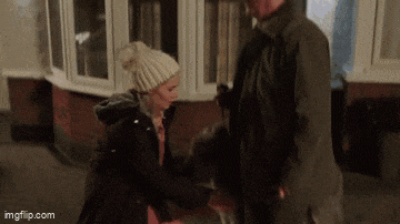 a man and a woman are standing in front of a house .