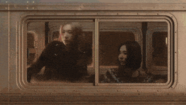 two women are looking out a train window